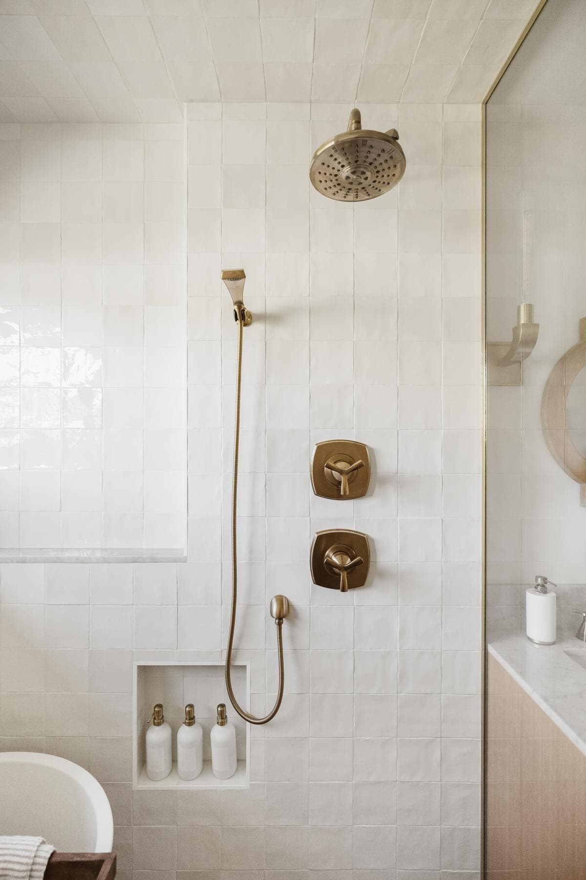 Bright, sleek bathroom shower with brass showerhead and controls for elegant appeal.