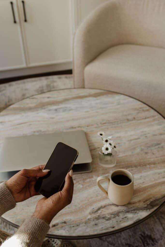 A cozy staged living room featuring a marble coffee table, a laptop, and a cup of coffee, perfect for home selling staging services.