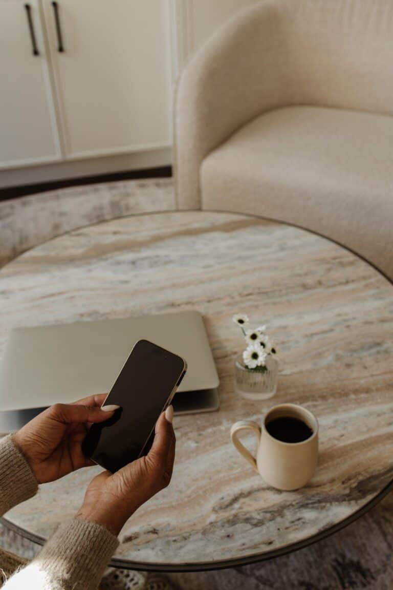A cozy staged living room featuring a marble coffee table, a laptop, and a cup of coffee, perfect for home selling staging services.