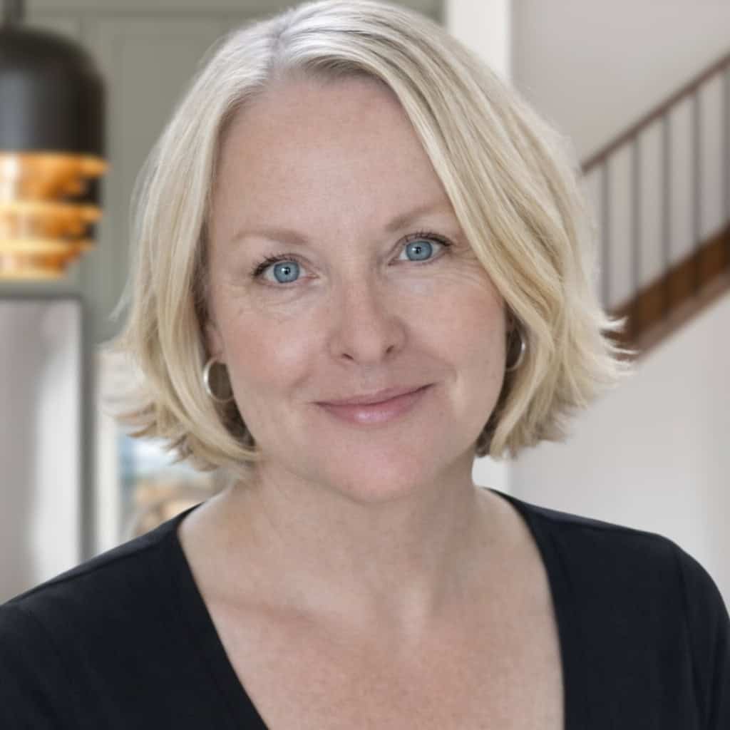 Close-up of smiling woman with blonde hair indoors.