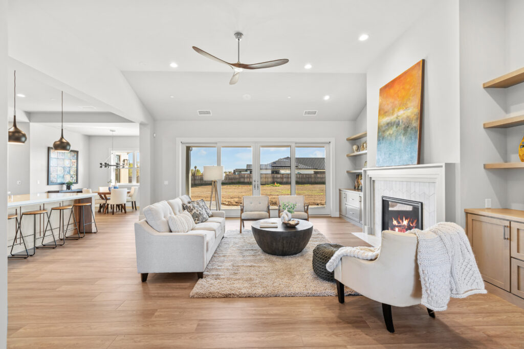 Beautifully styled living room with neutral sofa and chairs and vibrant art over fireplace.