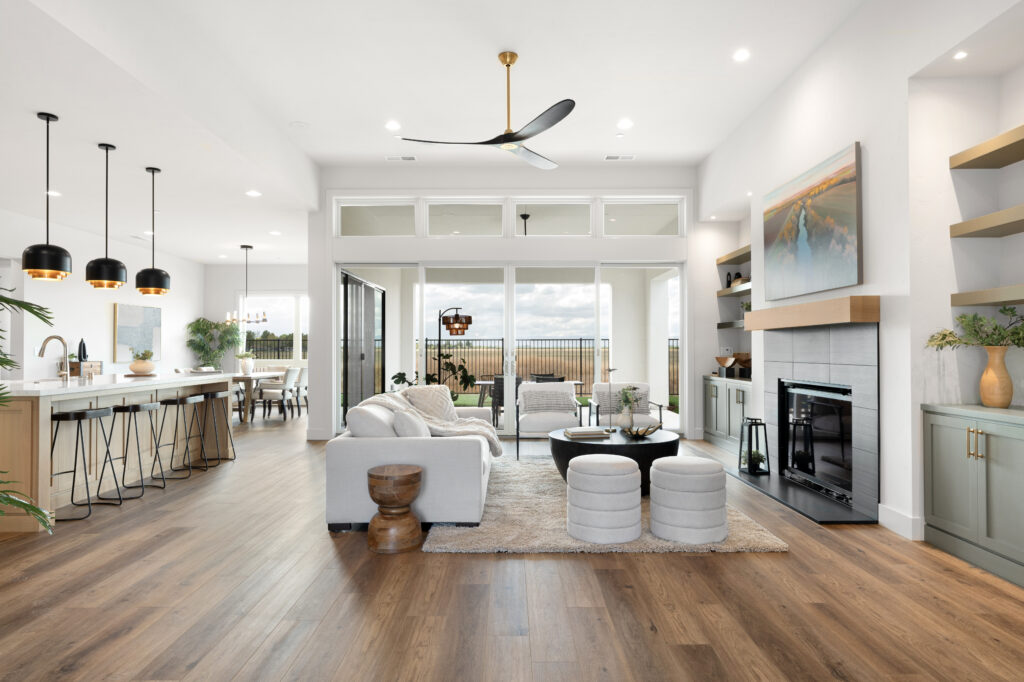Living room with sofa, side and coffee table, ottomans, chairs, big window in the background and a fireplace on the right.