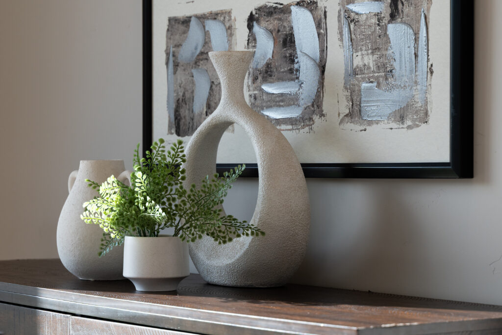 Dresser with accessories on the top and contemporary artwork on the wall over it.