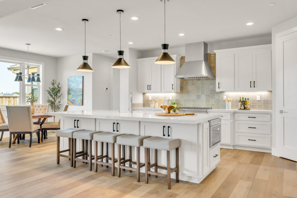 Kitchen with three black pendant lights hanging over an island and five barstools.