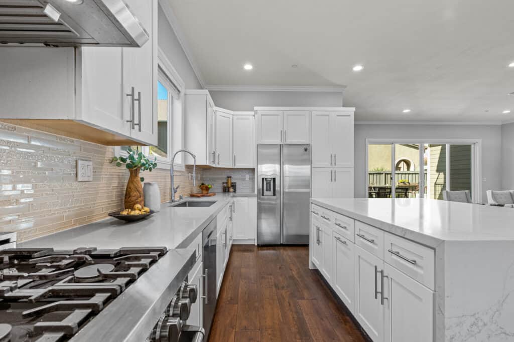 Bright, spacious kitchen with white cabinetry, stainless steel appliances, and elegant backsplash.